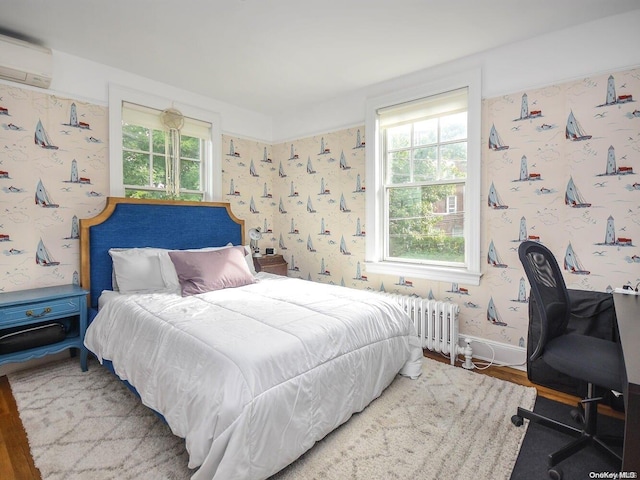 bedroom with hardwood / wood-style floors, radiator heating unit, a wall mounted AC, and multiple windows