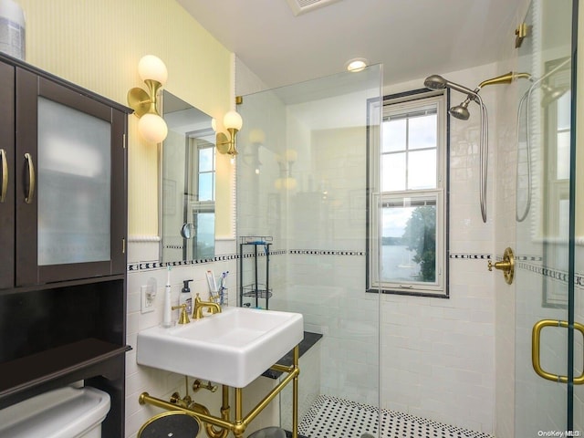 bathroom featuring toilet, sink, tile walls, and walk in shower