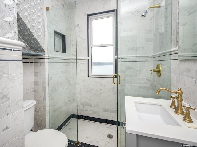 bathroom featuring vanity, toilet, a shower with door, and tile walls