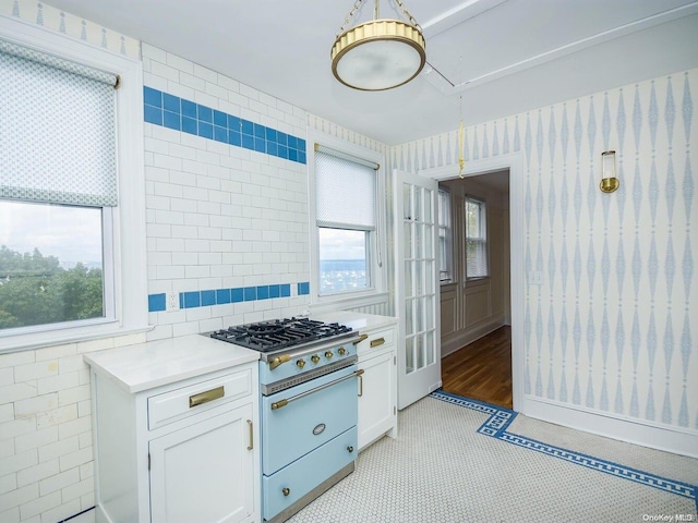 kitchen featuring high end stove, white cabinets, a healthy amount of sunlight, and light tile patterned floors