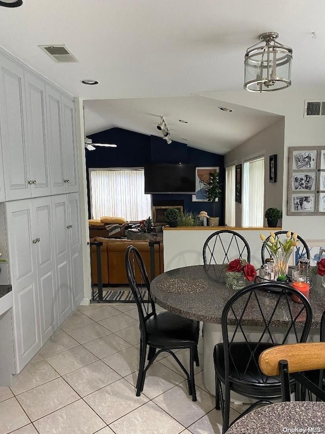 tiled dining room with ceiling fan and vaulted ceiling