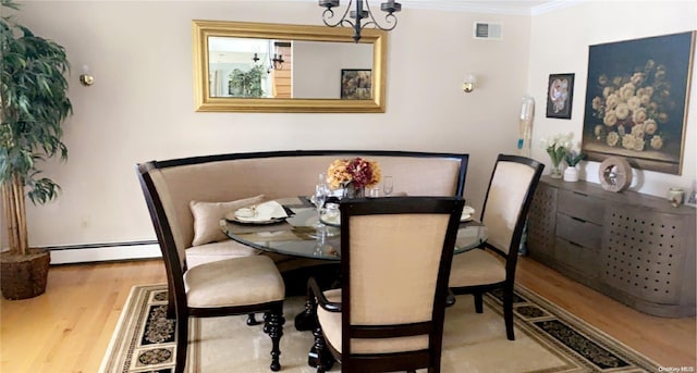 dining space with hardwood / wood-style flooring, an inviting chandelier, ornamental molding, and a baseboard radiator