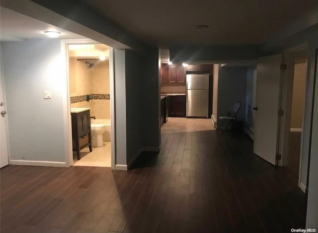 corridor with baseboard heating and hardwood / wood-style floors