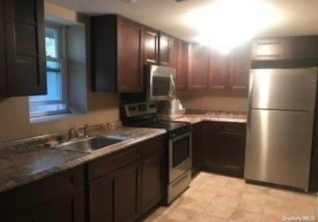 kitchen featuring dark brown cabinetry, sink, and appliances with stainless steel finishes