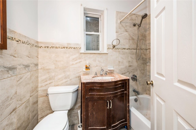 full bathroom with vanity, toilet, tiled shower / bath, and tile walls