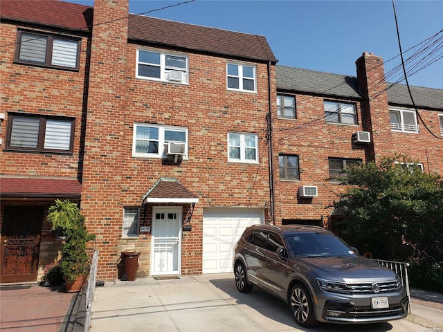 view of front of home featuring an AC wall unit and a garage