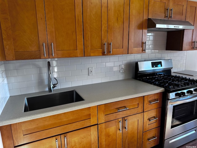 kitchen with decorative backsplash, stainless steel gas range oven, and sink