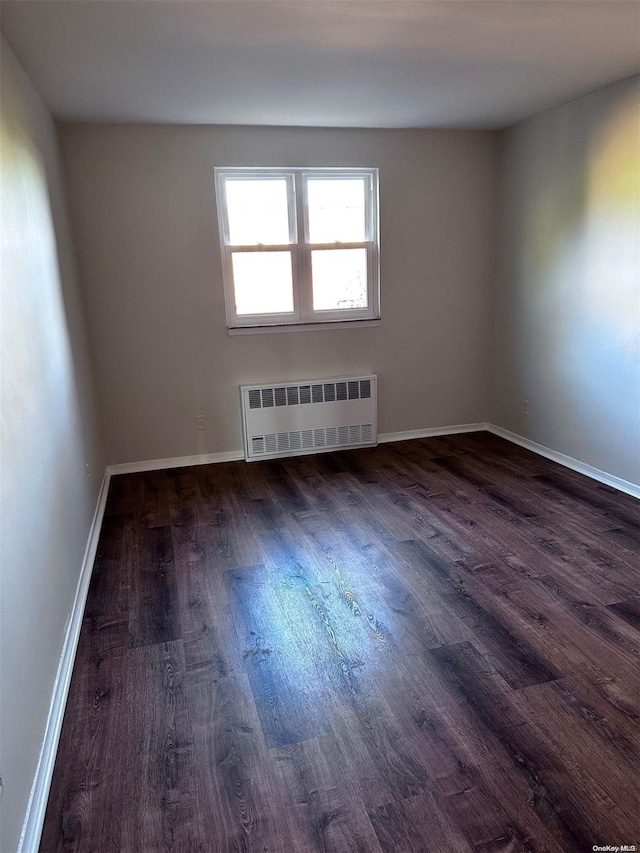 spare room featuring dark hardwood / wood-style flooring and radiator