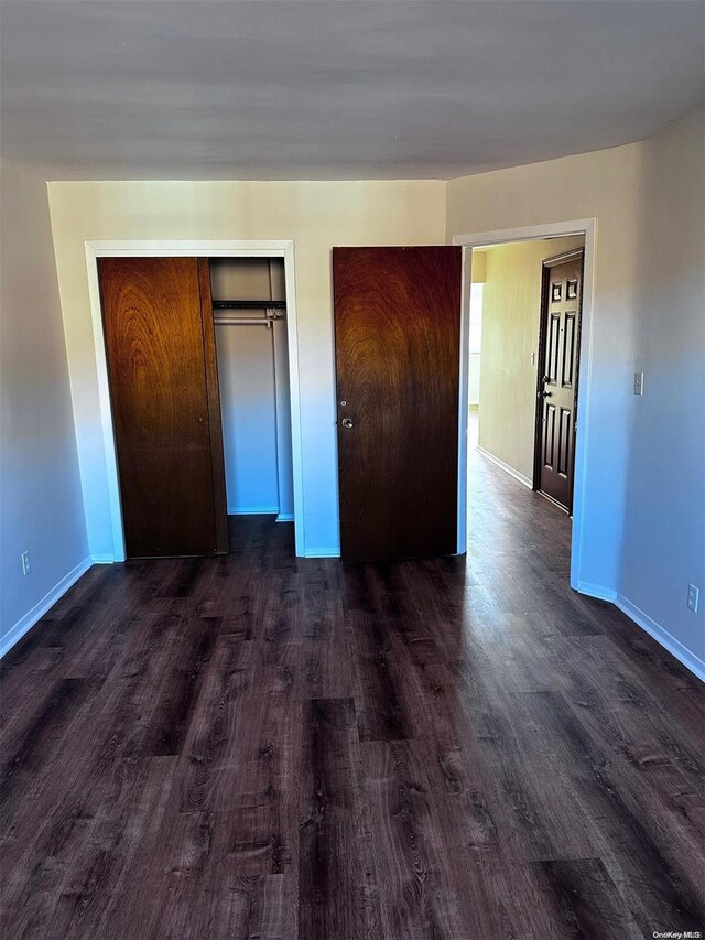 unfurnished bedroom with a closet and dark wood-type flooring