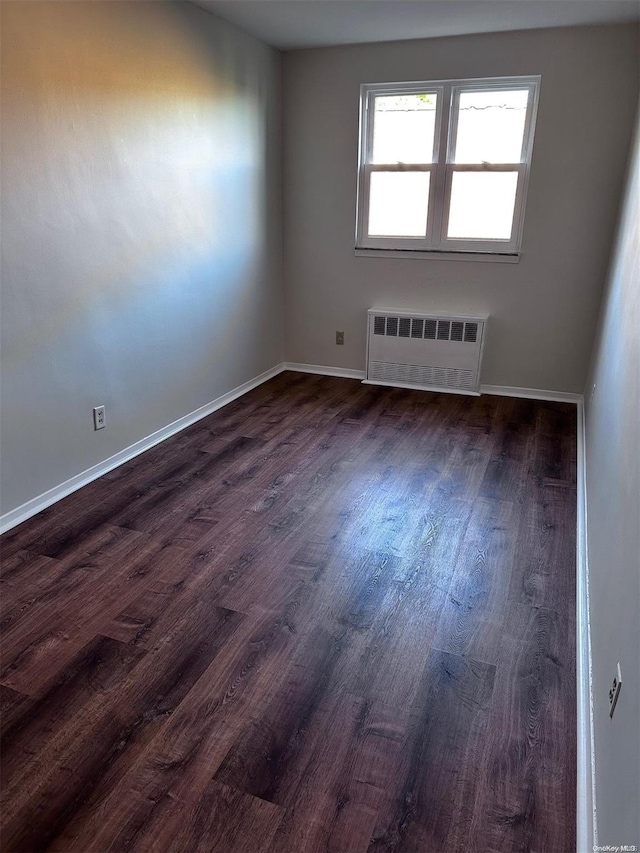 empty room featuring dark hardwood / wood-style flooring and radiator heating unit