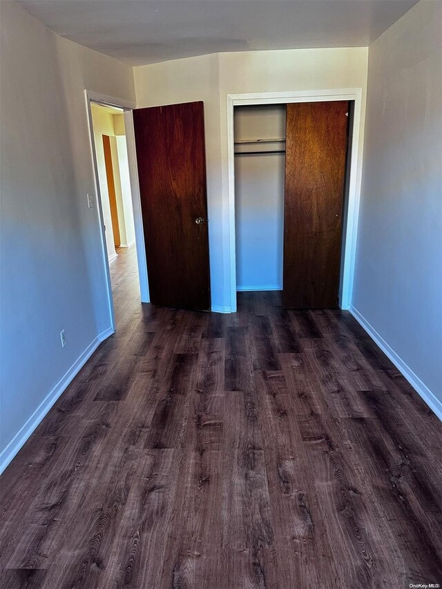 unfurnished bedroom with dark wood-type flooring and a closet