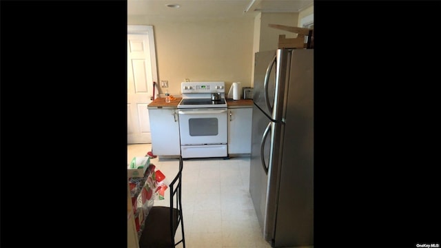 kitchen featuring butcher block countertops, white electric stove, and stainless steel refrigerator