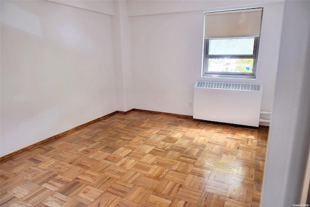 empty room with radiator heating unit and light parquet flooring