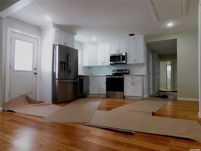 kitchen featuring backsplash, white cabinetry, stainless steel appliances, and light hardwood / wood-style flooring