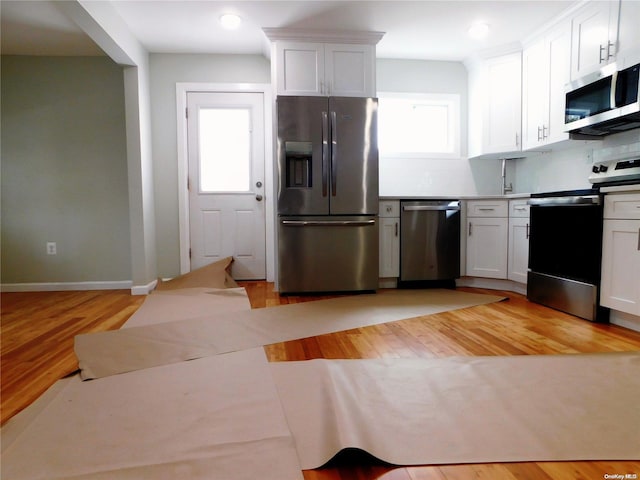 kitchen featuring backsplash, white cabinetry, stainless steel appliances, and light hardwood / wood-style floors