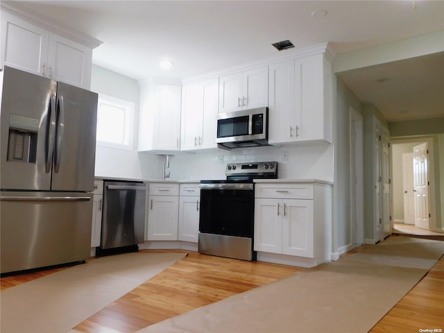 kitchen with white cabinets, stainless steel appliances, and light hardwood / wood-style flooring