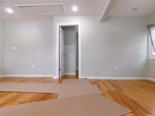 spare room featuring hardwood / wood-style floors and beamed ceiling