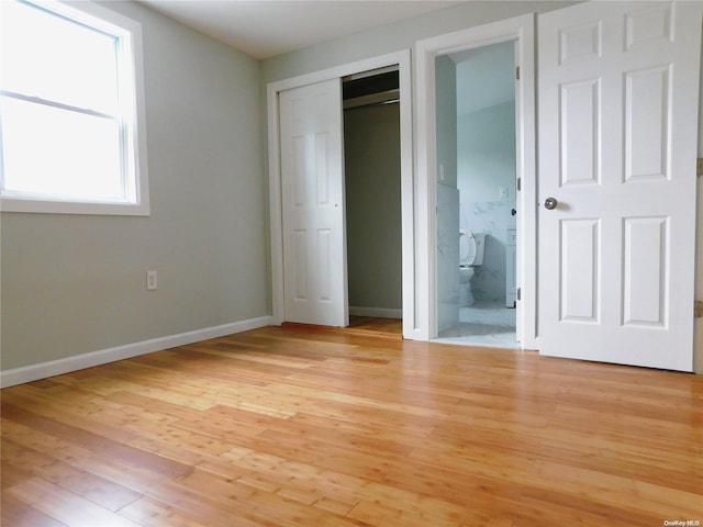 unfurnished bedroom featuring connected bathroom and light hardwood / wood-style flooring