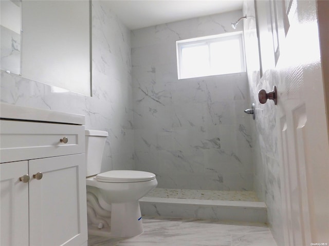 bathroom featuring a tile shower, vanity, and toilet