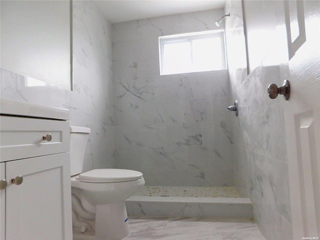 bathroom featuring a tile shower, vanity, and toilet