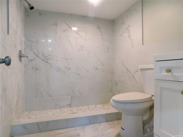 bathroom with toilet, a tile shower, tile walls, and vanity