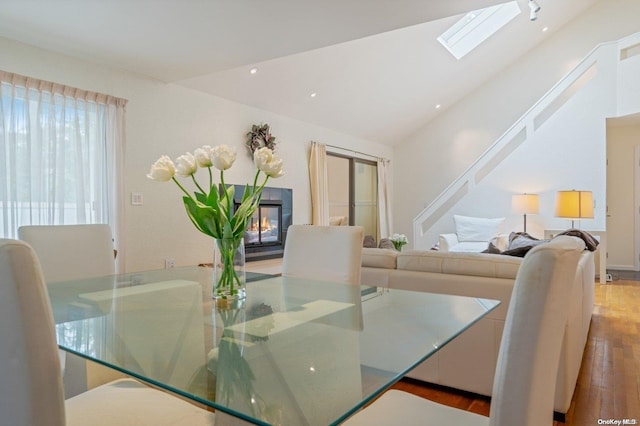 dining room featuring light hardwood / wood-style flooring and lofted ceiling with skylight