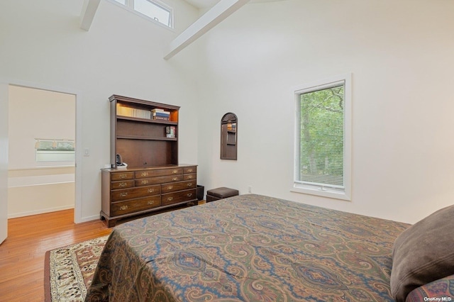 bedroom featuring beamed ceiling, light hardwood / wood-style floors, and high vaulted ceiling