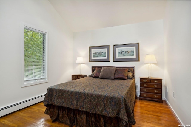 bedroom featuring a baseboard radiator, vaulted ceiling, and light wood-type flooring