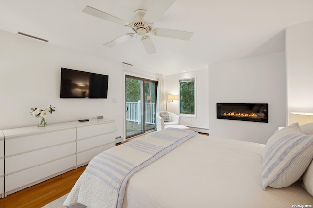 bedroom with access to outside, ceiling fan, light hardwood / wood-style flooring, and a baseboard radiator