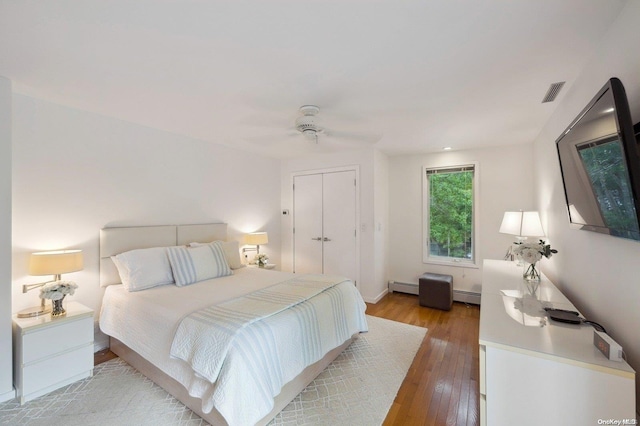 bedroom featuring baseboard heating, ceiling fan, and light hardwood / wood-style flooring