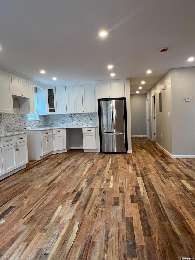 kitchen featuring decorative backsplash, stainless steel fridge, light wood-type flooring, and white cabinetry