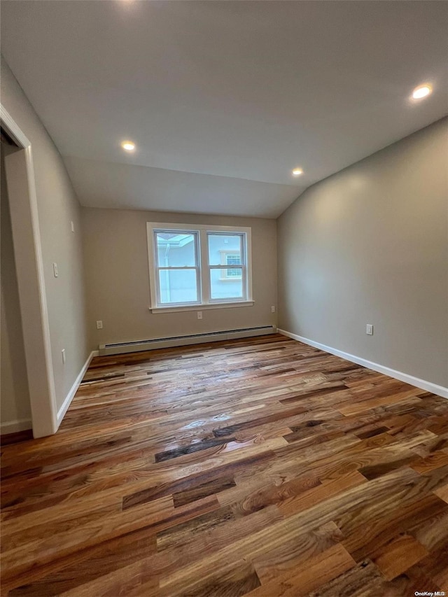 spare room featuring hardwood / wood-style flooring, lofted ceiling, and baseboard heating