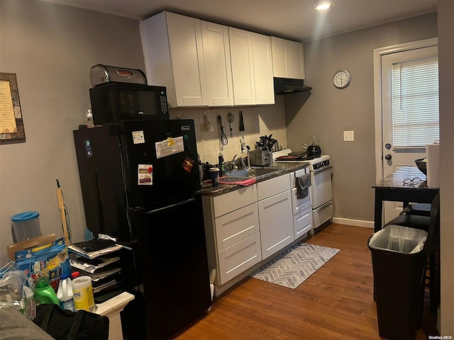 kitchen with black fridge, dark wood-type flooring, sink, white cabinets, and white stove