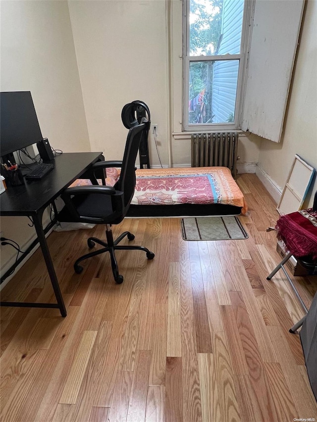 home office with light hardwood / wood-style flooring and radiator