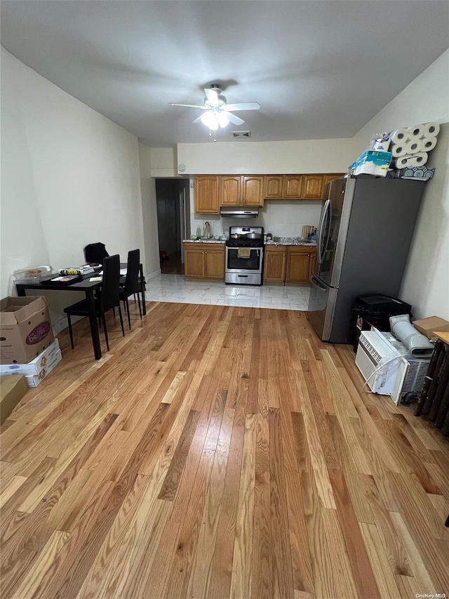 kitchen featuring ventilation hood, ceiling fan, light hardwood / wood-style floors, and stainless steel appliances