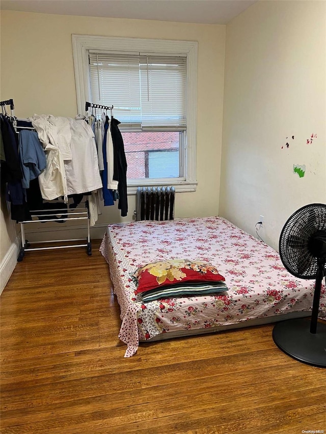 bedroom with radiator heating unit and hardwood / wood-style floors