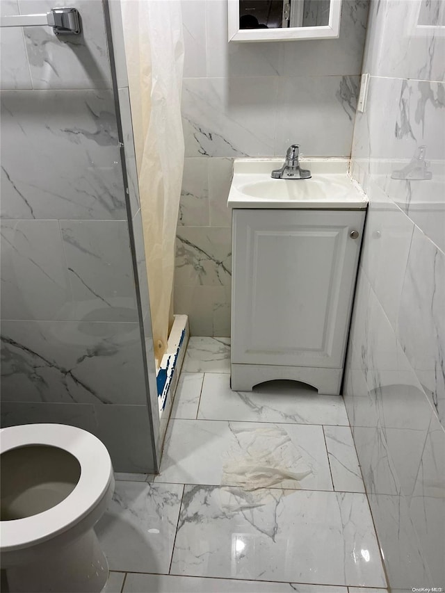 bathroom featuring walk in shower, vanity, baseboard heating, tile walls, and toilet