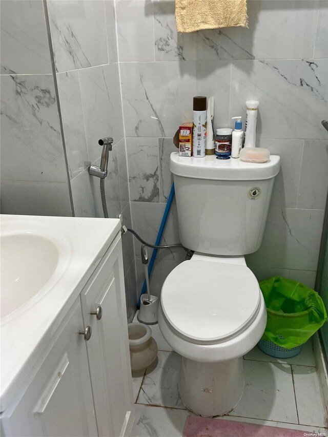 bathroom with vanity, toilet, and tile walls