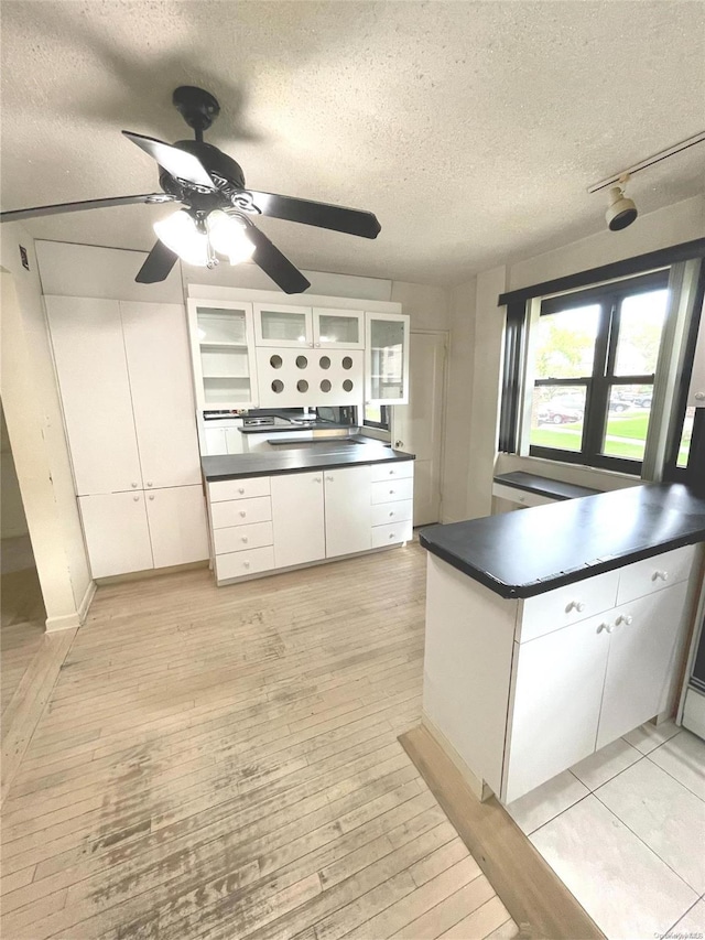 kitchen featuring white cabinets, a textured ceiling, and light hardwood / wood-style flooring