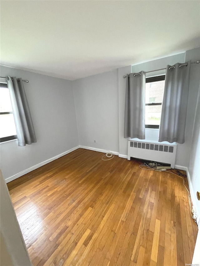 spare room featuring radiator heating unit and hardwood / wood-style flooring