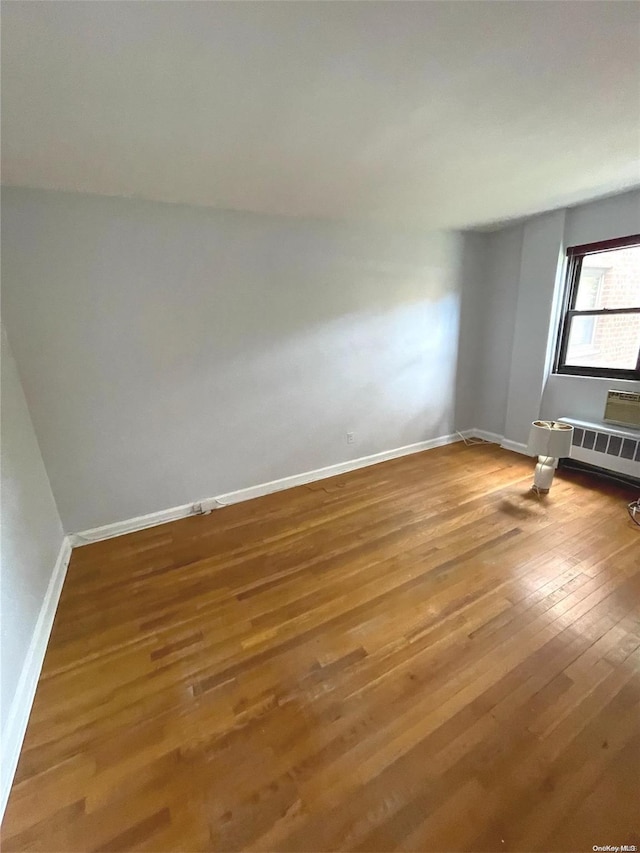 empty room with wood-type flooring and radiator