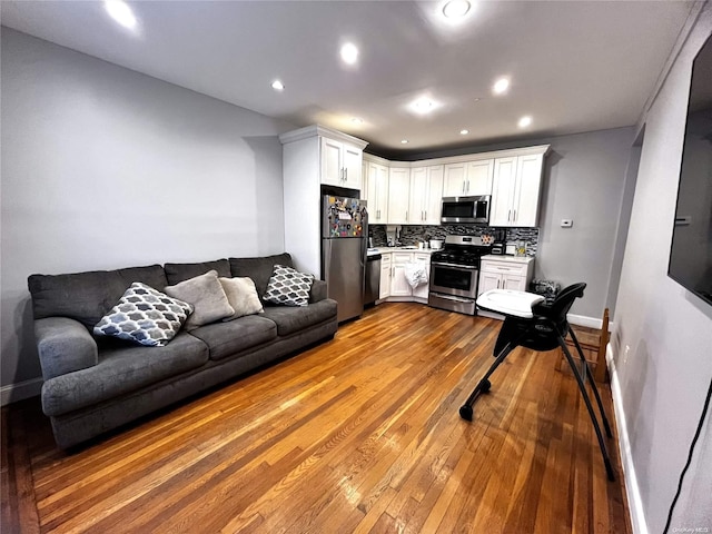 kitchen with white cabinets, appliances with stainless steel finishes, light hardwood / wood-style floors, and tasteful backsplash