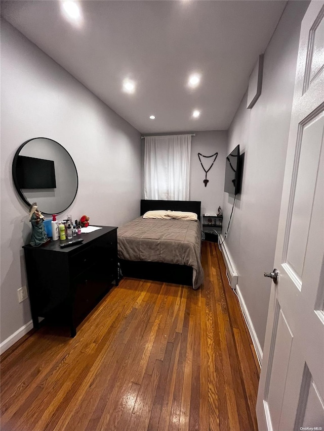 bedroom with baseboard heating and dark wood-type flooring