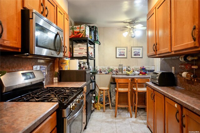 kitchen featuring appliances with stainless steel finishes, tasteful backsplash, light tile patterned floors, and ceiling fan