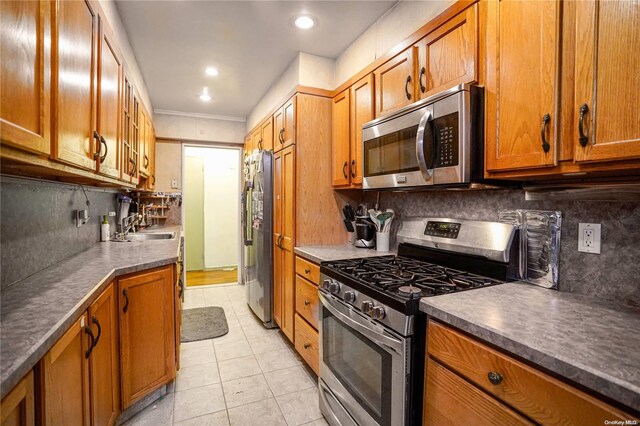 kitchen with backsplash, light tile patterned floors, stainless steel appliances, and ornamental molding