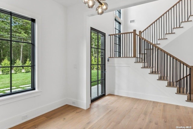 entrance foyer featuring a notable chandelier, a healthy amount of sunlight, and light wood-type flooring