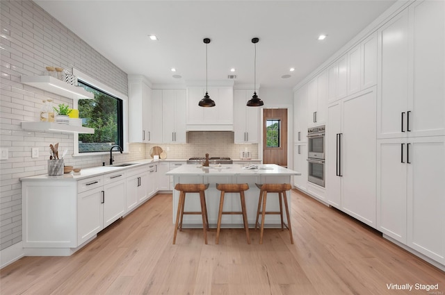 kitchen with white cabinetry, a kitchen island with sink, a healthy amount of sunlight, and sink