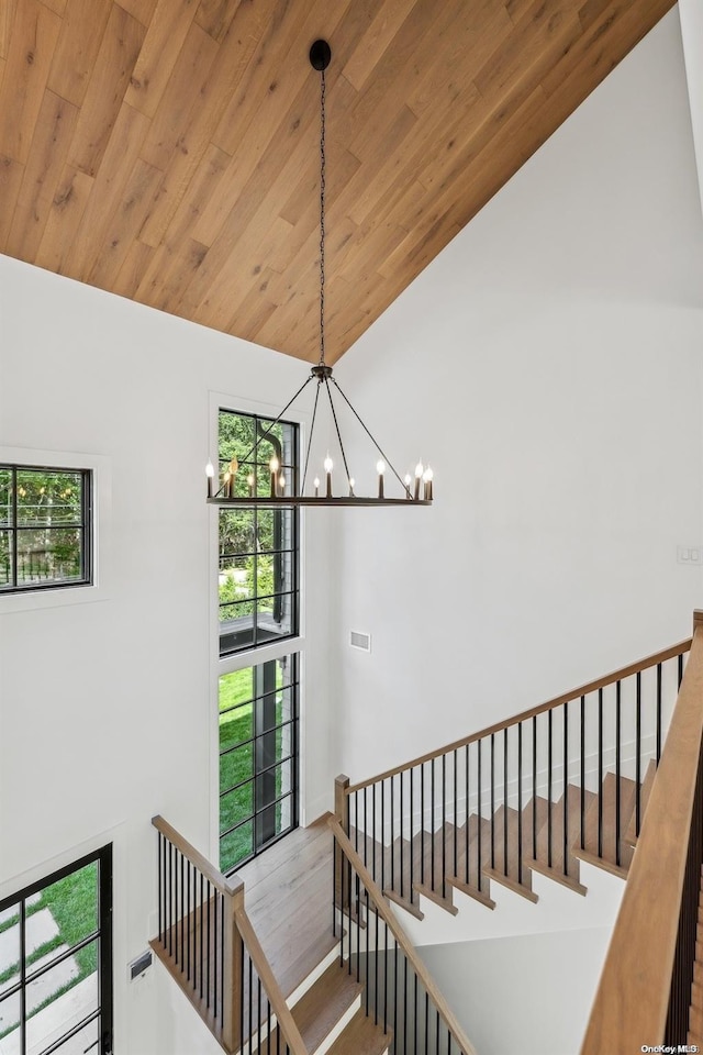 staircase featuring hardwood / wood-style floors, wooden ceiling, vaulted ceiling, and an inviting chandelier