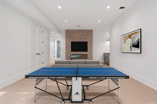 rec room with light tile patterned flooring and a tiled fireplace