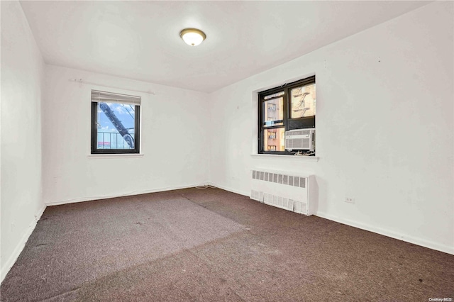 carpeted empty room featuring cooling unit and radiator heating unit